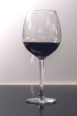 Red wine on a wineglass on a white background close up still