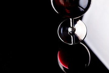 Naklejka na ściany i meble Red wine on a wineglass over a dark solid black background