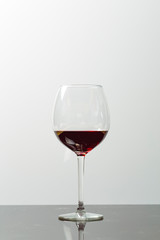 Red wine on a wineglass on a white background close up still