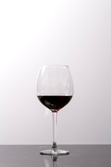 Red wine on a wineglass on a white background close up still