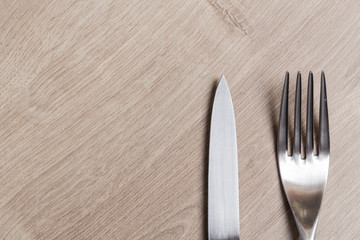 Silver modern knife and fork cutlery on a wooden table