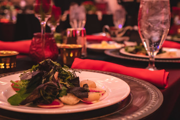 Fancy salad dinner on red banquet tables during an event.