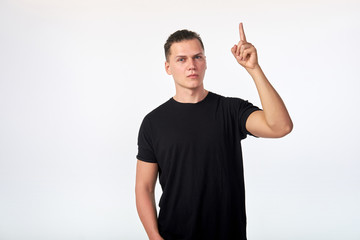 Fototapeta premium Young attractive serious man raising his index finger demanding attention.