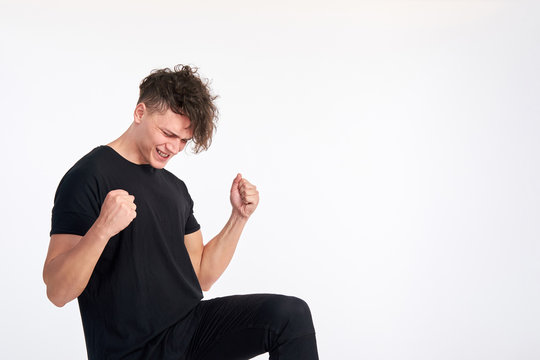 Happy satisfied young man celebrating and cheering a success bending elbows like gesture yes against white background. Positive feelings. Studio shot on white background.