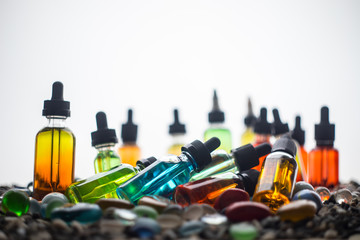 Vape concept. Beautiful colorful vape liquid glass bottles outdoor on stones. Useful as background...