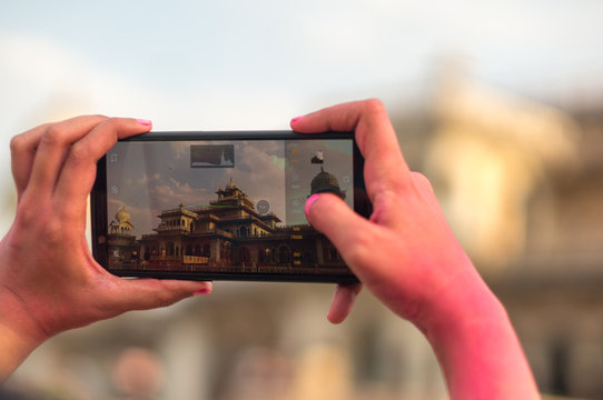 Tourist taking a photo of the famous albert hall in jaipur with a mobile phone 