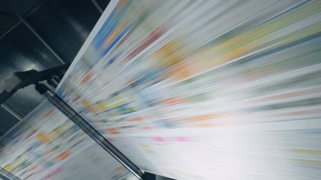 Colored newspaper rolling on a typography conveyor, automated machine.