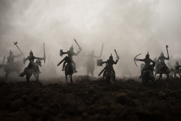 Fototapeta na wymiar Medieval battle scene with cavalry and infantry. Silhouettes of figures as separate objects, fight between warriors on sunset foggy background. Selective focus