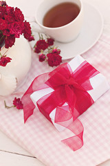Composition with white gift box with red ribbon