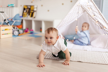 Couple adorable toddlers enjoying movement and simple games playing in cosy sunny nursery kindergarten for infants.