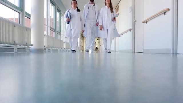 Drei &Auml;rzte im Flur von Krankenhaus unterhalten sich kurz 
