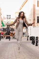 young woman with long brown hair happily bounces on the background of the street