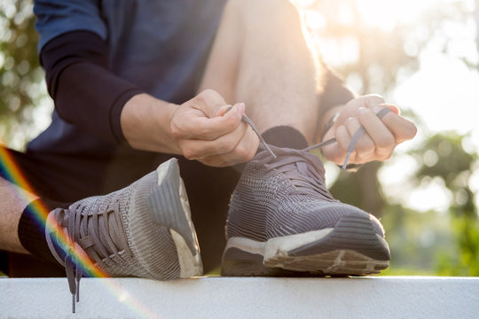 Male athlete tying shoe laces in minimalistic barefoot sneakers getting ready for training. Sport workout and healthy lifestyle concept