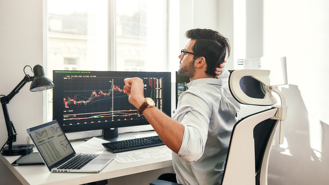 Overworked. Back view of tired young beard businessman or trader in formal wear touching his head and stretching while sitting in office.