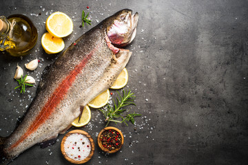 Raw salmon fish whole with ingredients for cookings on black.