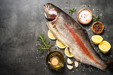 Raw salmon fish whole with ingredients for cookings on black.