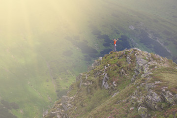 Girl Tourist on the peak of high rocks at sunny day. Sport and active life concept