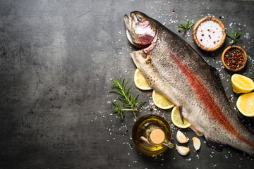 Raw salmon fish whole with ingredients for cookings on black.