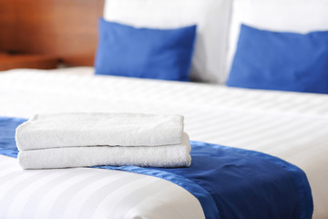 Freshly laundered fluffy towels on bed in hotel room