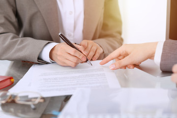 Businesswoman signing contract papers. Group of business people at meeting or negotiation, close-up