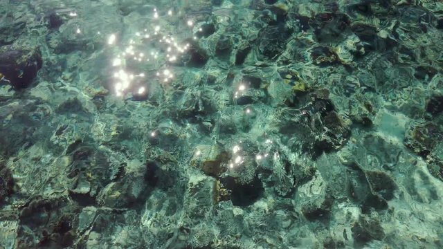 Top shot of the seabed. The sunshine makes the crystal clear water surface sparkle.