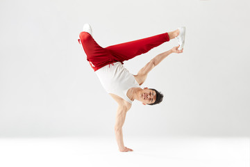 Athletic young b-boy standing on one hand while dancing break dance and doing downrock isolated...