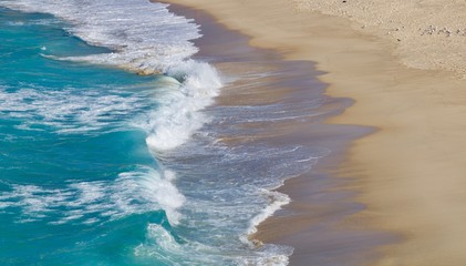 Waves lapping onto a sandy beach - image