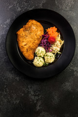 Pork meat served with potato and salad on plate