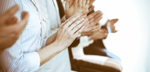 Business people clapping and applause at meeting or conference, close-up of hands. Group of unknown businessmen and women in modern white office. Success teamwork or corporate coaching concept