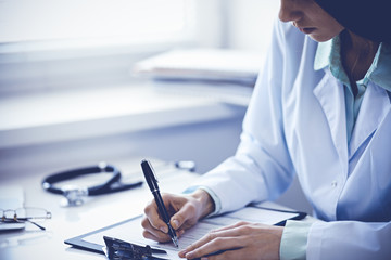Close up of  unknown female doctor sitting  at the table near the window in hospital
