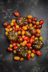 Fototapeta na wymiar Raw organic colorful tomatoes on dark slate background