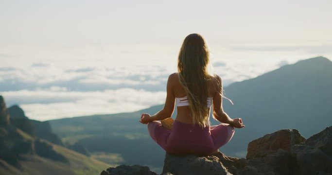 Young athletic woman meditating on the top of a mountain, zen yoga meditation practice in nature