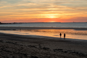 Fototapeta na wymiar St Malo, France - September 15, 2018: Romantic walk of people before sunset on the picturesque beach of Saint Malo. Brittany, France