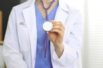 Unknown doctor woman holds stethoscope head, close-up. Physician ready to examine and help patient. Helping and insurance in health care, best treatment and medicine concept