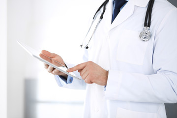 Doctor man using tablet computer for network research or virtual disease treatment, hands close-up. Perfect medical service in clinic. Modern  medicine, medic data and healthcare concepts