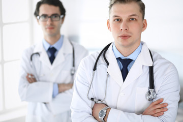 Doctor man standing straight with colleague at background. Group of doctors. Perfect medical service in clinic. Medicine and healthcare concepts