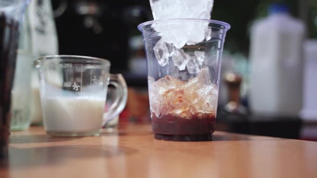 Hand pouring and mixing coffee with milk for making iced latte drink
