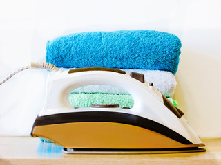 Stack of colorful clean towels  on white background. Ironing clothes on ironing board. Stack of...