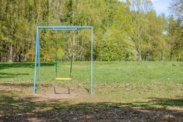 Fototapeta na wymiar Old chain swing in the sun in the spring park