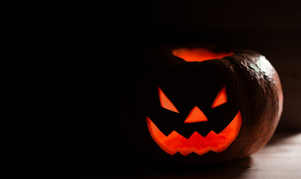 creepy smiling pumpkin for Halloween on black background.
