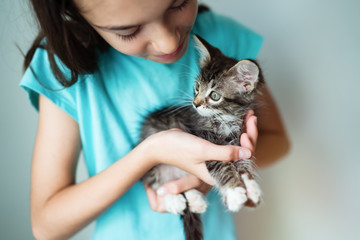 Cute child girl holding a kitten in her arms