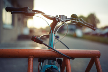 Girl teenager fastening bicycle lock on street parking at sunset