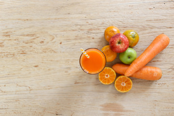 Mix orange juice, carrots, apples on a wooden floor.