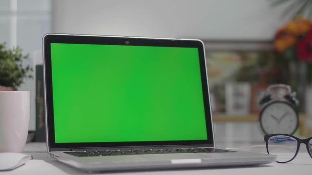 Woman working on the laptop computer with green screen at home. Chroma key. View from the back. 