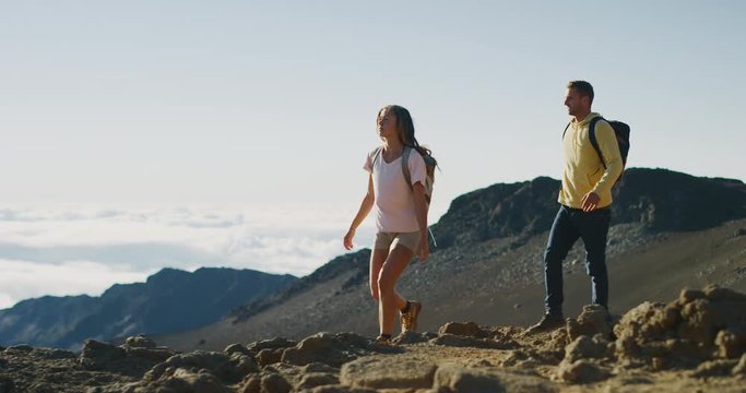Young adventurous couple hiking together on the top of a mountain in slow motion, summer wilderness excursions