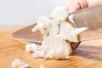 cook cuts onion on a wooden board