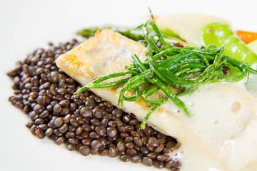 Grilled zander with black lentils, mixed green vegetables and lemon foam