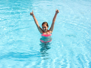 Naklejka premium Young teen girl swims and have fun in the outdoor pool