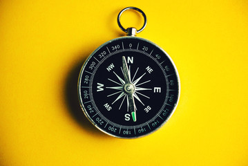 Compass on yellow background, minimal-travel-concept.