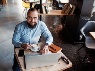 Businessman bearded man in a suit works behind the laptop sitting in a comfortable office coworking.